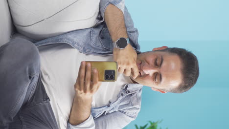 Vertical-video-of-Happy-man-texting-on-the-phone.-Smiling.